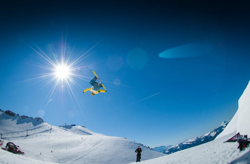 Snowboarder backflipping over snoy jump