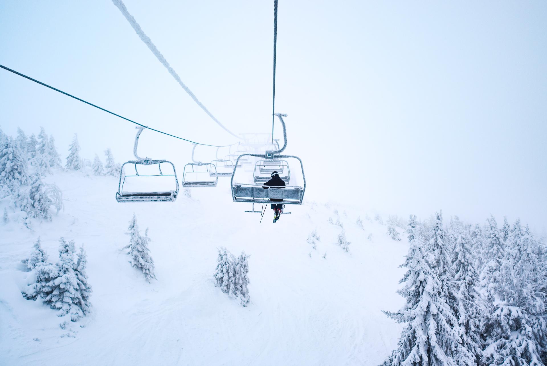 Snowy chair lift with a single skier on it