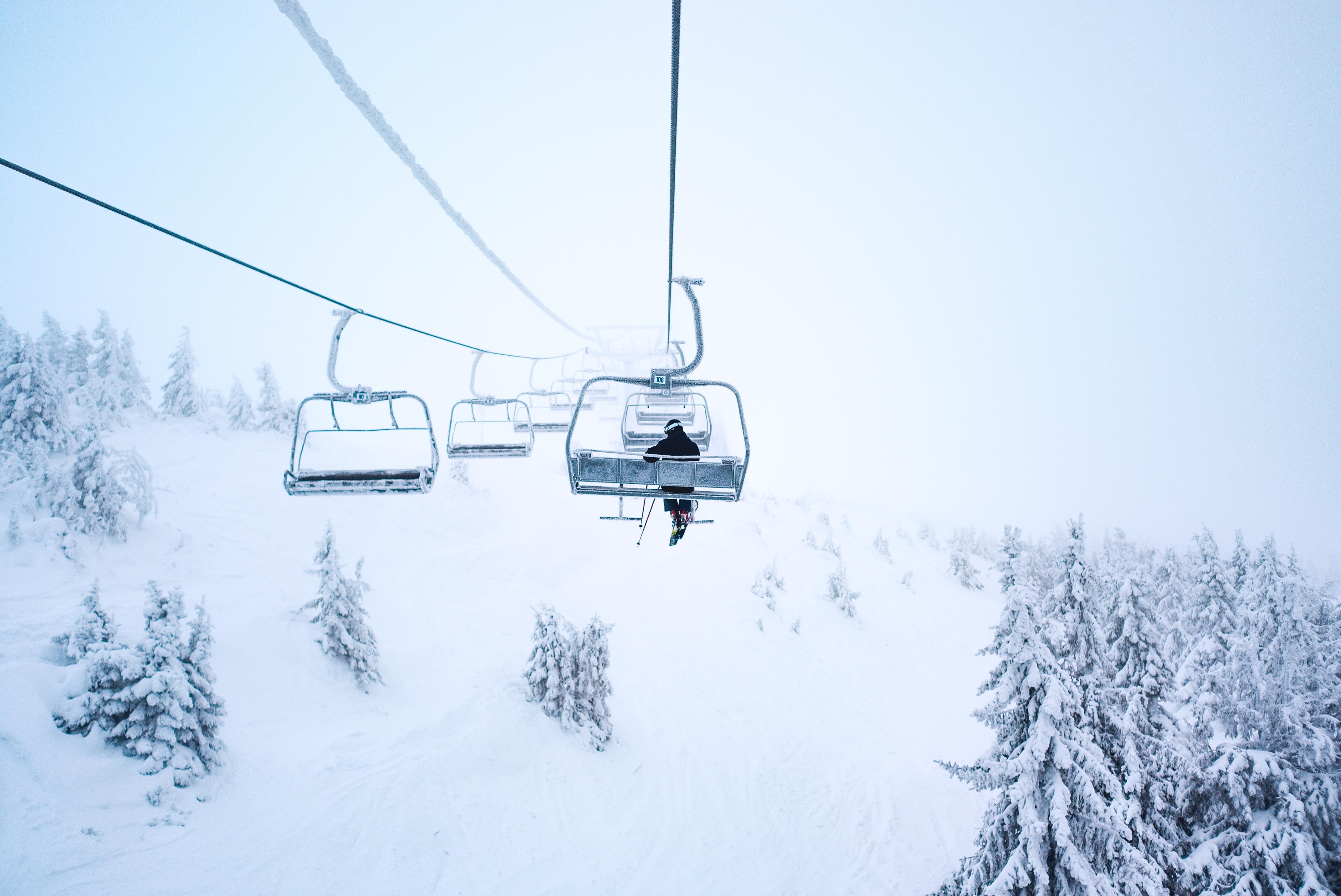 Snowy chair lift with a single skier on it